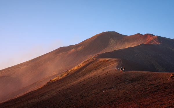 Sunrise view of Mount Etna with clear sky and golden light over black lava fields